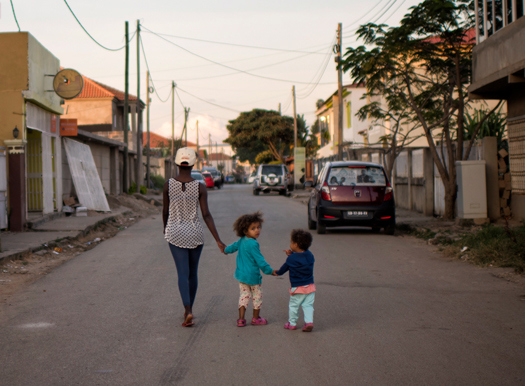 A mother and her two kids walk down a street years after the clearance of mines