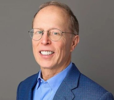 John Jameson smiling, posing in front of a neutral background