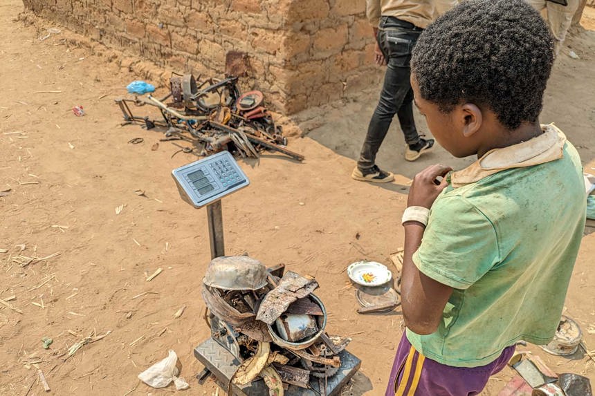 A young boy weighs scrap metal in Angola
