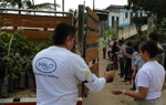 A man in a HALO shirt hands out potted tree seedlings to be passed down a line of people.