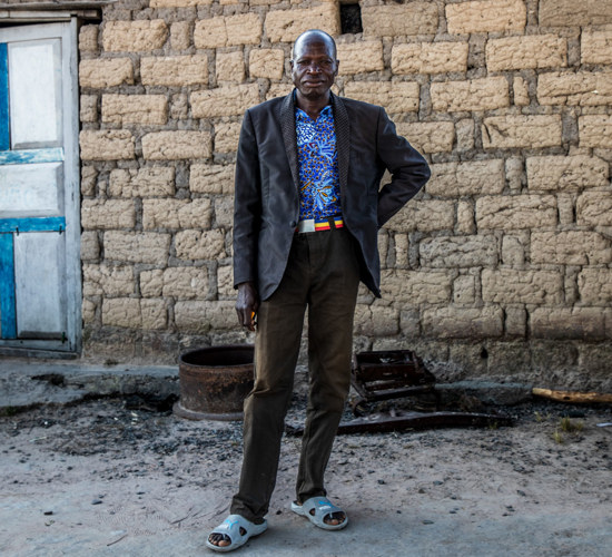 Faustino Jorge, village leader, stands outside of a house in Angola