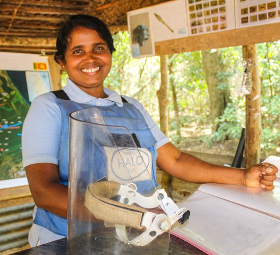 Sasikumar Kolkila, HALO Deputy Area Supervisor, stands in PPE while holding a visor
