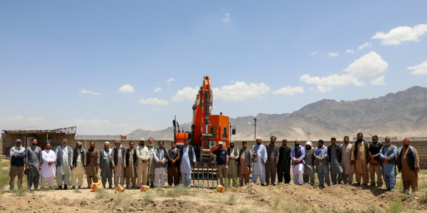 Mine action operators stand in front of construction vehicle used for mechanical IED training