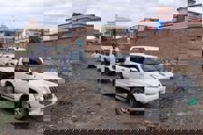 3 men stand outside 3 vehicles in Khost