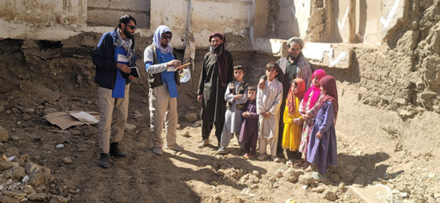 A family and two HALO staff stand in a house contaminated with IEDs