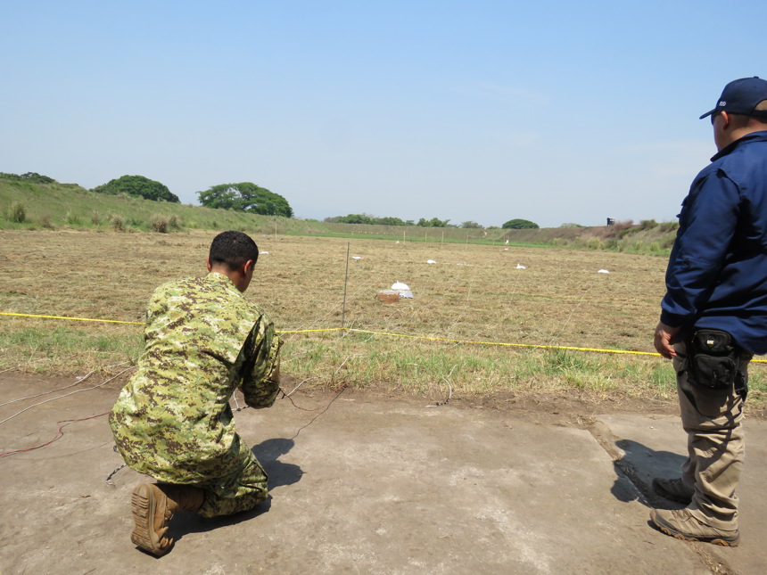 Military personnel demonstrates explosive effects on a field during the explosive ordnance disposal course