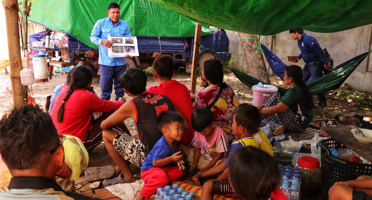 A member from the explosive ordnance risk education team speaks to adults and children outside