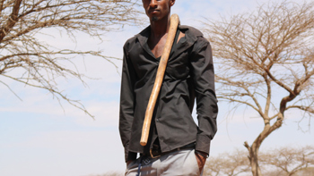 Abdul Nasser a goat herder in Somaliland stands with a walking stick over his shoulder