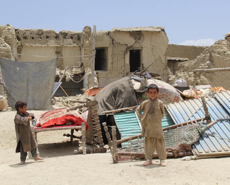 Two boys outside a house destroyed by the earthquake in Afghanistan