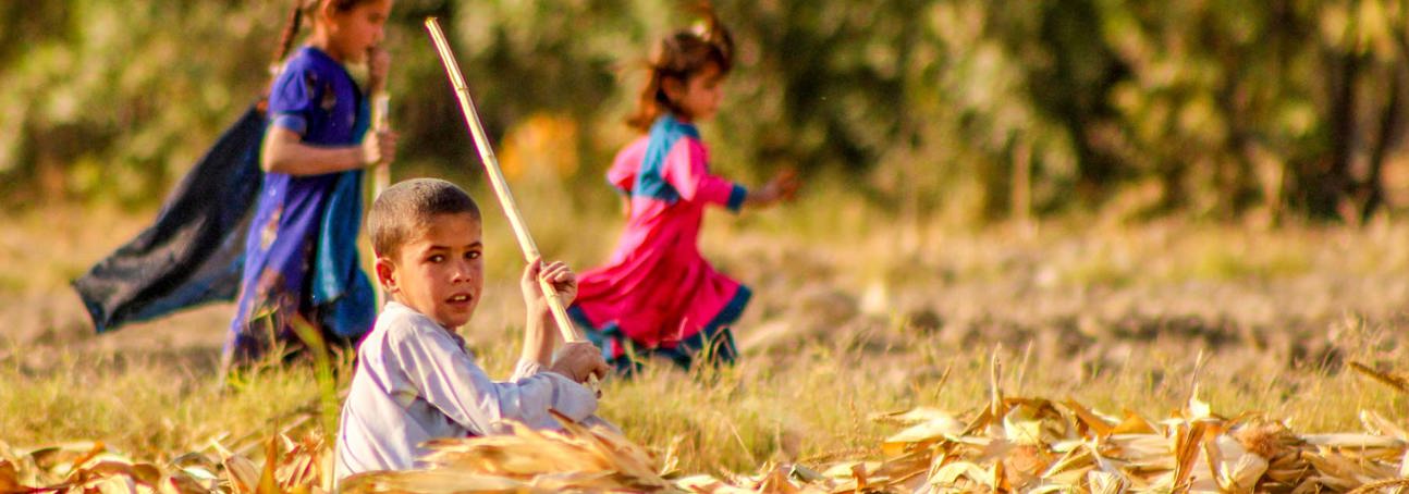 A group of three children play in a field in Afghanistan