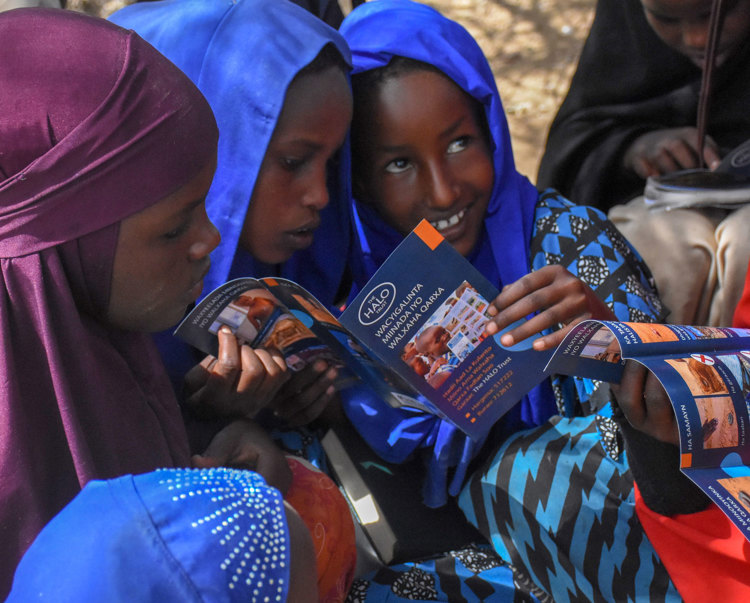 Children from a risk education session in Mandheera village hold a HALO booklet
