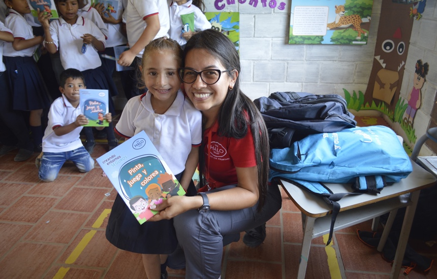 A HALO risk educator poses with a school child in a class after a explosive ordnance risk education session
