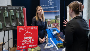 An attendee speaks with a HALO staff member across an exhibition table