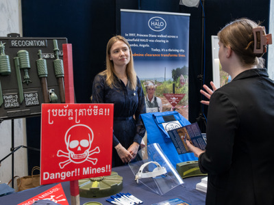 An attendee speaks with a HALO staff member across an exhibition table