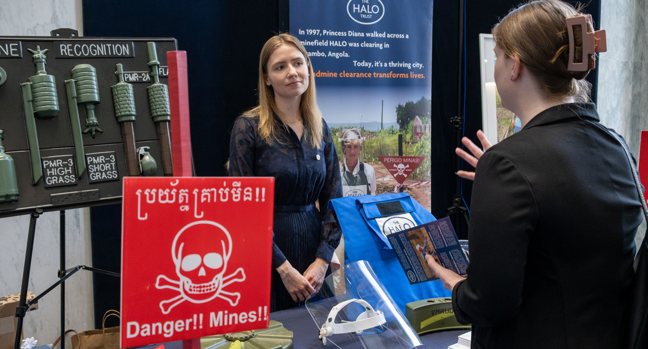 An attendee speaks with a HALO staff member across an exhibition table