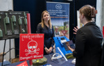 An attendee speaks with a HALO staff member across an exhibition table