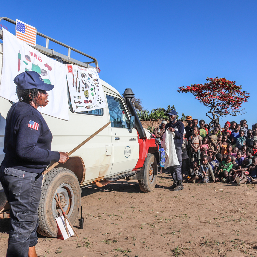 A HALO staff member delivers an EORE session pointing to a banner on a vehicle