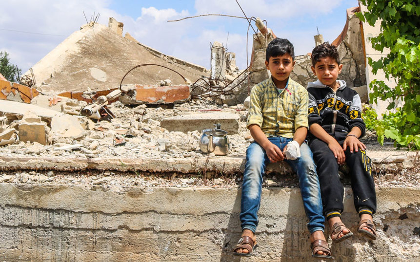 Two young boys sit on a wall in Syria