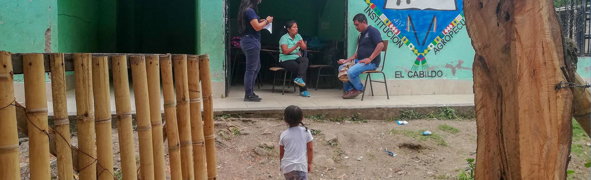 Halo staff sit and talk with a woman outside El Cabildo school