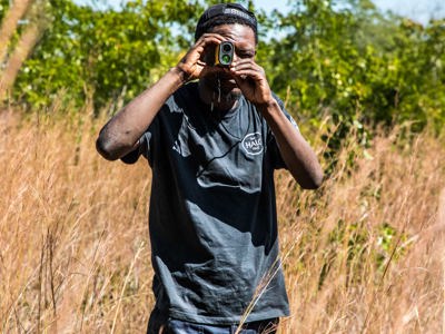 A HALO staff member looks through binoculars in a field
