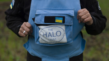 A light blue HALO Trust vest with the Ukrainian flag above it.