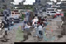 Residents of Khost gather round HALO medical professional as he treats a man on the ground