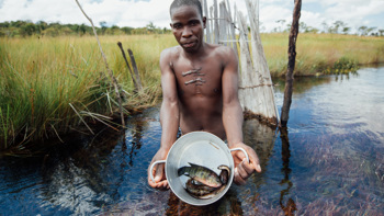 A man holds up a bucket containing fish he has just caught in Angola