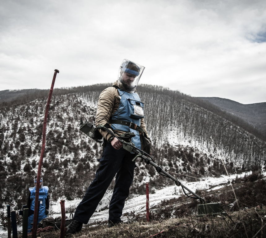 A HALO deminer in PPE scans for explosives on the snowy hills of Kosovo