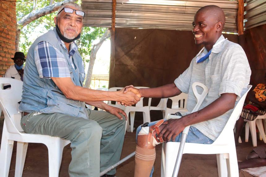 A landmine survivor with a prosthetic leg shakes hands with Dr Cassim in HALO's clinic