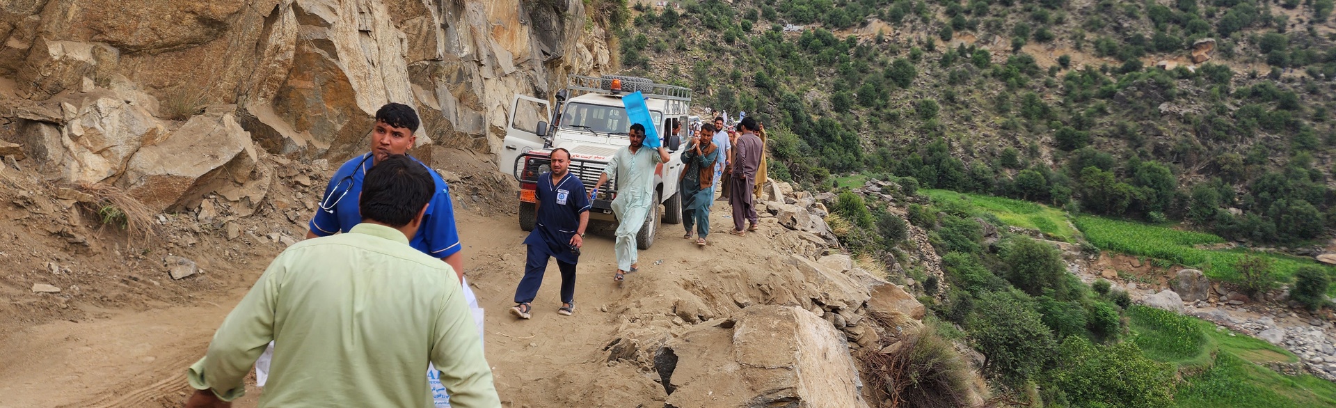 Trucks and personnel travel up a mountainside in Afghanistan.