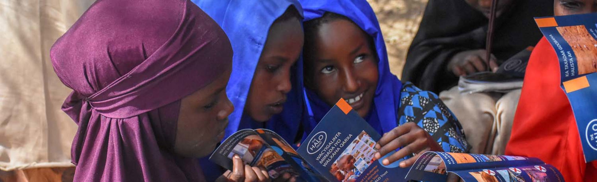 Children from a risk education session in Mandheera village hold a HALO booklet