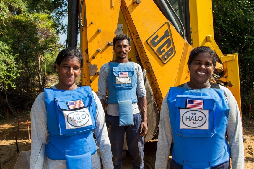 A mechanical clearance team wear PPE next to a digger in Sri Lanka