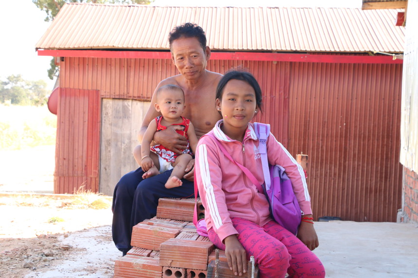 A man sits on top of a stack of bricks with his two children