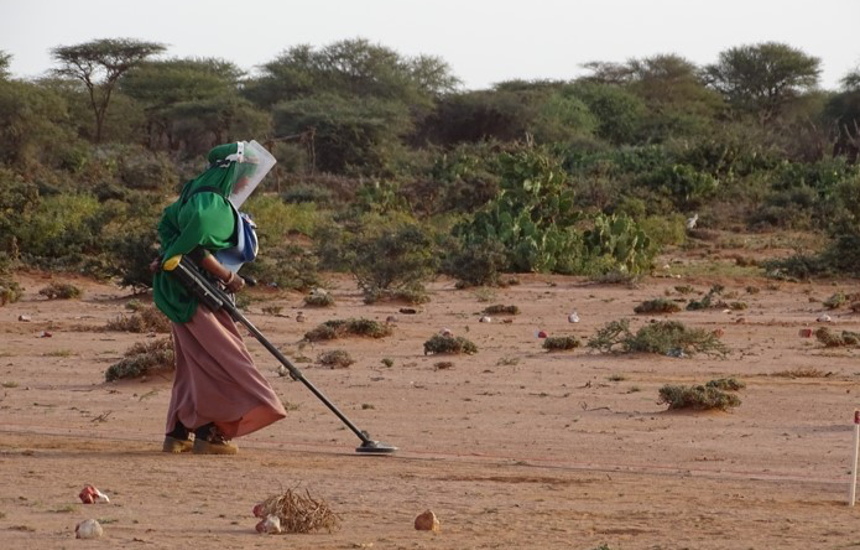 A female deminer using a metal detector on a rural minefield in Somaliland