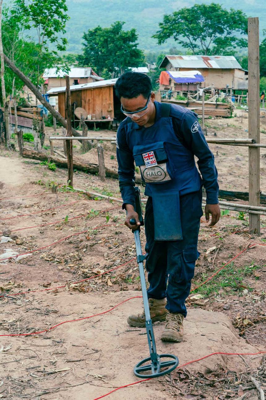 A deminer in Vangkhot village hovers a detector over the ground