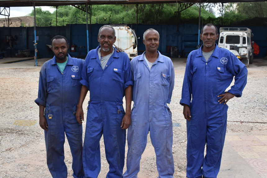 Four HALO staff members in overalls pose together outside