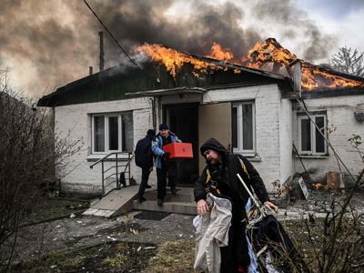 Three people flee a burning house carrying their belongings