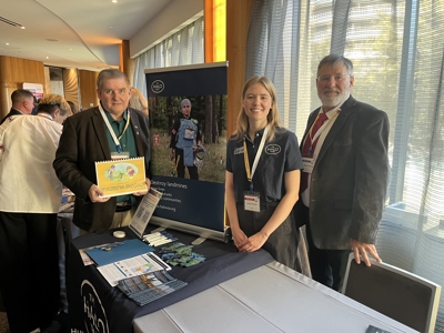 Three people pose for a photo at an exposition booth.