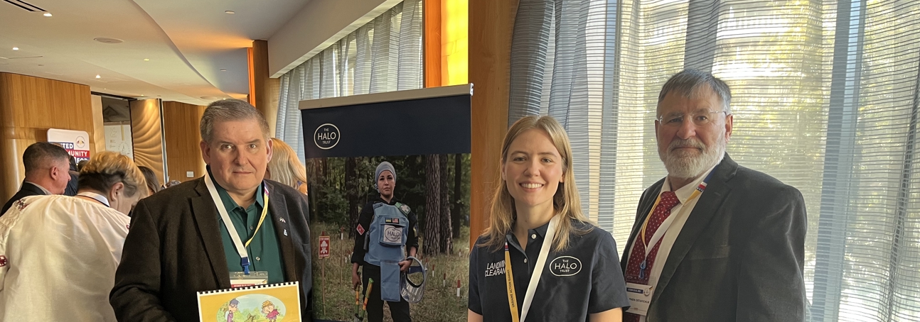 Three people pose for a photo at an exposition booth.