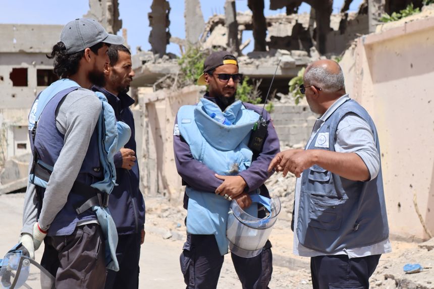 HALO staff wear PPE in front of collapsed buildings