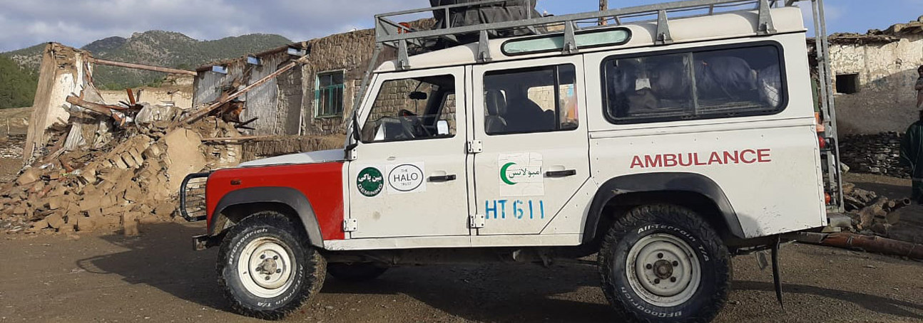 HALO land rover used as an ambulance with destroyed buildings in the background