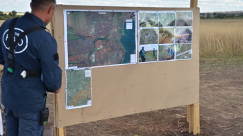 A HALO staff member looks at a task map pinned onto a board in a minefield