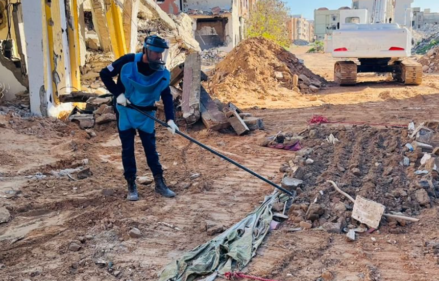A deminer rakes through rubble in Sirte, Libyra