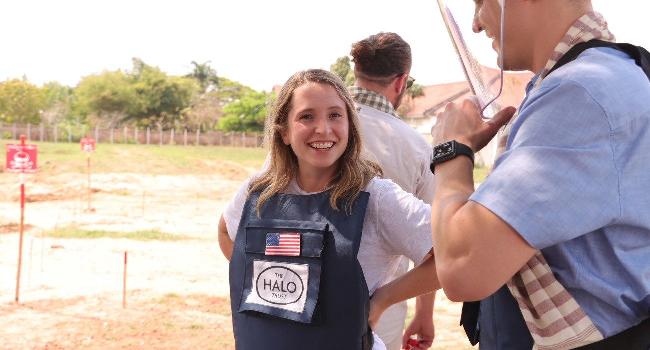 US Congressional staffers wear PPE in front of a mine marked field