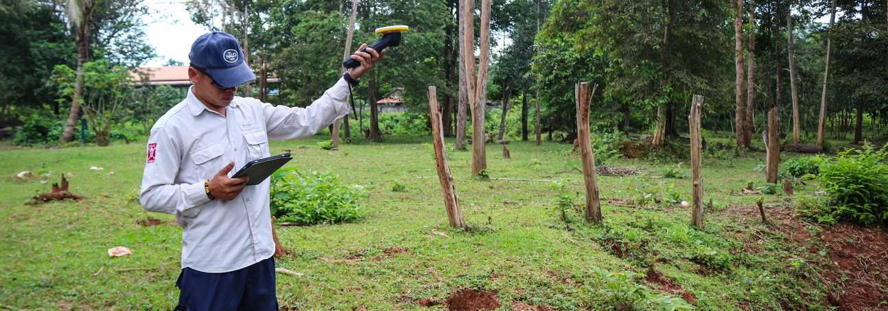 A field data collector in Laos uses a Trimble DA2 GNSS receiver to map survey areas for explosive contamination