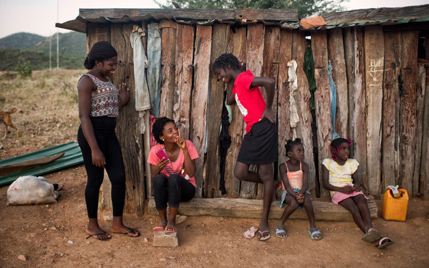 Three Angolan women chatting next to two kids