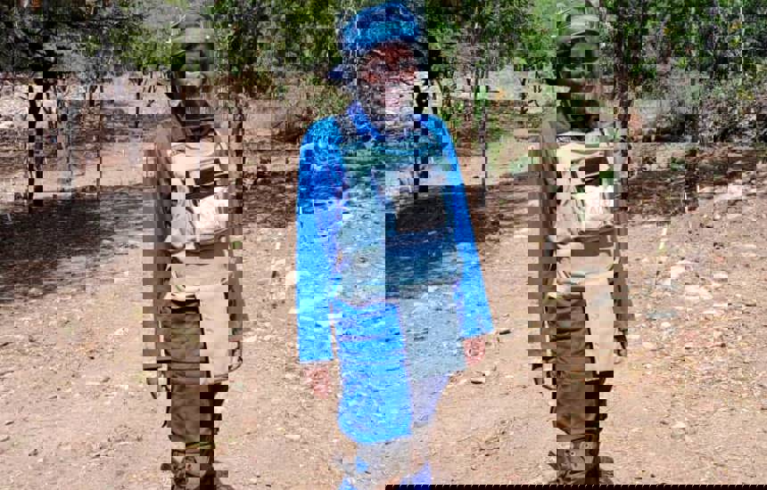 Delight Manyange, GIS Specialist, wears HALO uniform and PPE in a minefield in Zimbabwe