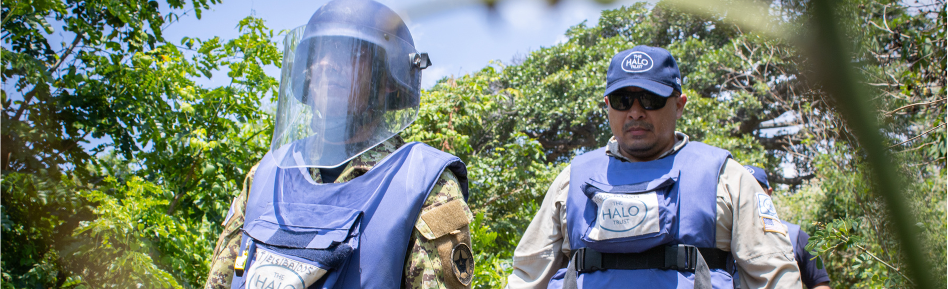 Captain Flores, wears PPE and walks through a forest with a HALO technician