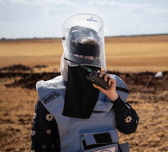 HALO woman deminer wearing PPE on a minefield in Syria