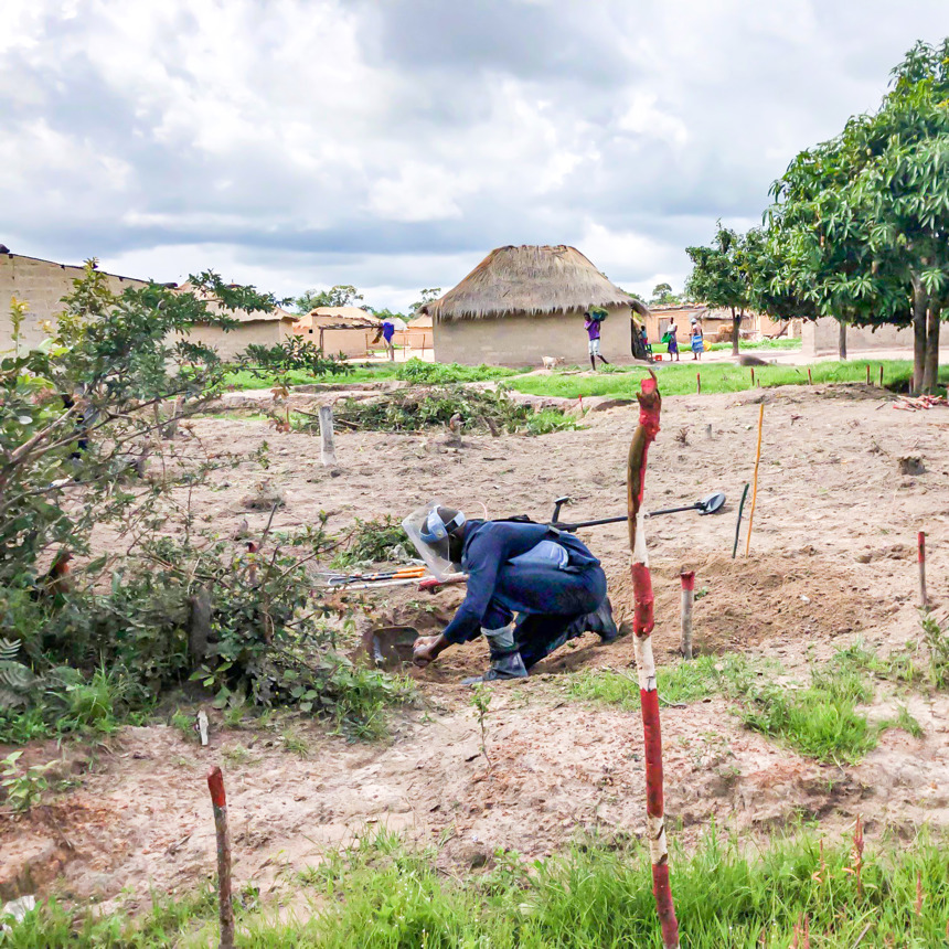 A deminer crouches for an excavation in Angola